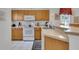 Well-lit kitchen with white appliances, light wood cabinets, and a breakfast bar overlooking the dining area at 8452 Crystal Cove Loop, Kissimmee, FL 34747