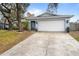 Home exterior featuring an attached garage, a well-manicured lawn, and mature trees at 851 Benchwood Dr, Winter Springs, FL 32708