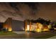Striking modern home featuring a combination of wood and metal accents, enhanced by professional nighttime landscape lighting at 8966 Easterling Dr, Orlando, FL 32819