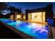 Gorgeous illuminated pool stretches alongside the modern home, visible dining area through large glass doors at 8966 Easterling Dr, Orlando, FL 32819