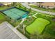 Aerial view of community amenities, including a tennis court, putting green, and parking, all surrounded by well-manicured landscaping at 8995 Croquet Ct, Champions Gate, FL 33896