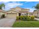 Charming two-story home with a two-car garage, brick driveway, stone accents, and well-manicured landscaping at 8995 Croquet Ct, Champions Gate, FL 33896