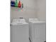 Bright laundry room features modern, white washer and dryer and upper shelving at 8995 Croquet Ct, Champions Gate, FL 33896