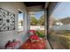 Screened porch with bright sunlight, a red patio chair, and a view into the backyard at 105 Pine Street, Windermere, FL 34786