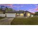 Charming one-story home with a two-car garage with manicured lawn under twilight sky at 112 Lake Butler Ave, Haines City, FL 33844