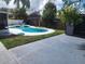 This backyard features a kidney-shaped pool, green grass, a shed, and a concrete patio at 11419 Aries Dr, Orlando, FL 32837