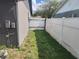 Side yard view of a home featuring a narrow grassy area and white fence at 11419 Aries Dr, Orlando, FL 32837