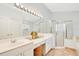 Bathroom featuring a large mirror, dual sinks, white cabinetry, a glass-enclosed shower, and a soaking tub at 13537 Ivy Brooke Ln, Orlando, FL 32828