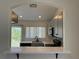 Kitchen pass-through featuring granite countertops, grey cabinets, black appliances, and tile backsplash at 13900 Corrine Key Pl, Orlando, FL 32824