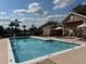 Community pool with lounge chairs and umbrellas next to a clubhouse at 13900 Corrine Key Pl, Orlando, FL 32824