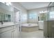 Elegant bathroom featuring double vanity, soaking tub with tile, and glass-enclosed shower at 15165 Heron Hideaway Cir, Winter Garden, FL 34787