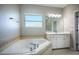 Bright bathroom featuring a soaking tub with tile surround, a vanity with cabinets, and natural light at 15165 Heron Hideaway Cir, Winter Garden, FL 34787