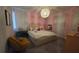 Cozy bedroom featuring a bed with a tufted headboard, a quirky hanging lamp, and soft pink walls at 1731 Caribbean View Ter, Kissimmee, FL 34747