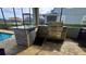 Screened outdoor kitchen with stainless steel grill, sink, mini fridge and granite countertops, great for entertaining at 1731 Caribbean View Ter, Kissimmee, FL 34747