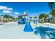 A vibrant outdoor water park features a slide, splash features, lounge chairs, and swaying palm trees under a sunny blue sky at 1731 Caribbean View Ter, Kissimmee, FL 34747
