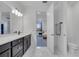 Bright bathroom with double vanity, sleek black cabinets, quartz countertop, a large mirror and access to a bedroom at 2012 Keystone Pass Blvd, Minneola, FL 34715