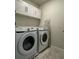 Laundry room with white appliances, ample cabinet space, and an ironing board at 2369 Palm Park Loop, Clermont, FL 34714