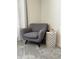 Cozy sitting area with gray armchair, patterned side table, and neutral carpet at 2369 Palm Park Loop, Clermont, FL 34714