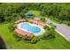 Aerial view of the community pool with red tile roofed cabanas, a playground, parking, and green space at 2554 Cypress Trace Cir, Orlando, FL 32825