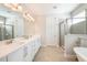 Bright bathroom featuring double sinks, a large mirror, and a glass-enclosed shower at 300 Burma St, Kissimmee, FL 34747