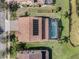 An aerial view of a home and backyard featuring a screened-in pool, solar panels, lush landscaping, and lake access at 4903 Eastlake Vista Dr, St Cloud, FL 34771