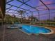 Stunning screened pool area with a spa, brick patio, and serene landscape views at twilight at 4903 Eastlake Vista Dr, St Cloud, FL 34771