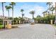 A gated community entrance with palm trees, well-maintained landscaping, and a brick-paved road at 5076 Tideview Cir # 90, Orlando, FL 32819