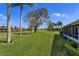 Expansive backyard with green grass, large trees, and landscaping that leads to a serene lake at 8011 Saint James Way, Mount Dora, FL 32757