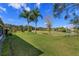Lush green backyard with mature palm trees and manicured lawn, offering plenty of outdoor space at 8011 Saint James Way, Mount Dora, FL 32757