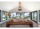 Open-concept living room with beamed ceiling, walls of windows, and stylish decor overlooking the water at 9575 Ne 306Th Ct, Fort Mc Coy, FL 32134
