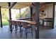 Inviting outdoor kitchen features a built-in grill, mini-fridge, bar seating, and wooden beam accents at 9575 Ne 306Th Ct, Fort Mc Coy, FL 32134