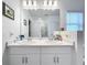 Bright bathroom featuring double sinks, quartz countertops, and a large mirror at 993 Calico Pointe Cir, Groveland, FL 34736
