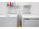 The laundry room has a washer and dryer with storage shelf and cleaning products at 993 Calico Pointe Cir, Groveland, FL 34736