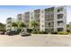 Exterior view of a white condominium building with screened balconies and lush landscaping at 1100 Delaney Ave # F204, Orlando, FL 32806