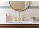 Close-up of a stylish bathroom sink with gold fixtures, decorative soap dispenser and a round mirror at 12 S Lawsona Blvd, Orlando, FL 32801