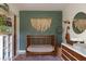 Stylish Bedroom with a wooden crib, green accent wall, patterned rug, and decorative wall hanging at 12 S Lawsona Blvd, Orlando, FL 32801