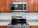 Close up of a stainless steel stove, oven and microwave with cherry wood cabinets at 1218 Falling Star Ln, Orlando, FL 32828