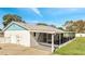 An exterior shot of the back of the home, featuring a screened-in lanai, white exterior, and manicured lawn at 161 Laurel Way, Kissimmee, FL 34743