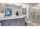 Modern bathroom features double sinks, sleek gray cabinetry, glass-enclosed shower, and stylish fixtures at 173 River Front Way, Edgewater, FL 32141