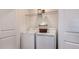 A well-lit laundry room with white washer and dryer, wire shelving and a storage basket at 177 River Front Way, Edgewater, FL 32141