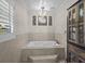 Relaxing bathroom showcases a jetted tub with tile surround and a decorative light fixture at 19 Meadowlake Ct, Winter Haven, FL 33884