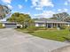 Charming single-story home with a manicured front lawn, mature trees, and a side-entry garage, showcasing curb appeal at 19 Meadowlake Ct, Winter Haven, FL 33884