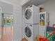 Convenient laundry room features a stacked washer and dryer and a storage cabinet, located near the outdoor pool access at 19 Meadowlake Ct, Winter Haven, FL 33884