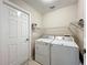 Functional laundry room with a washer, dryer, and overhead shelving for optimal organization at 21636 King Henry Ave, Leesburg, FL 34748