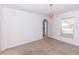 A carpeted room featuring an archway, woven lamp, and view of the front yard at 2645 Coachman Dr, Deltona, FL 32738