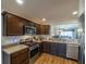 Spacious kitchen featuring stainless steel appliances, dark cabinets, and an open layout to the living area at 2936 Suber St, The Villages, FL 32163