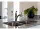 Close-up of a stainless steel kitchen sink with granite countertops, featuring modern fixtures and stylish green accents at 3380 Private Oak Dr, Apopka, FL 32703