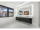 Modern bathroom features dual sinks, a black floating vanity, and a large, illuminated mirror above at 3845 S Stillwood Ln, Lake Mary, FL 32746