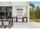 Outdoor kitchen with modern stainless steel appliances and a dining table, ideal for entertaining guests with green backyard views at 3845 S Stillwood Ln, Lake Mary, FL 32746