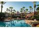 Resort-style pool area with palm trees, rock features, and a view of the clubhouse and tropical landscaping at 487 La Mirage St, Davenport, FL 33897